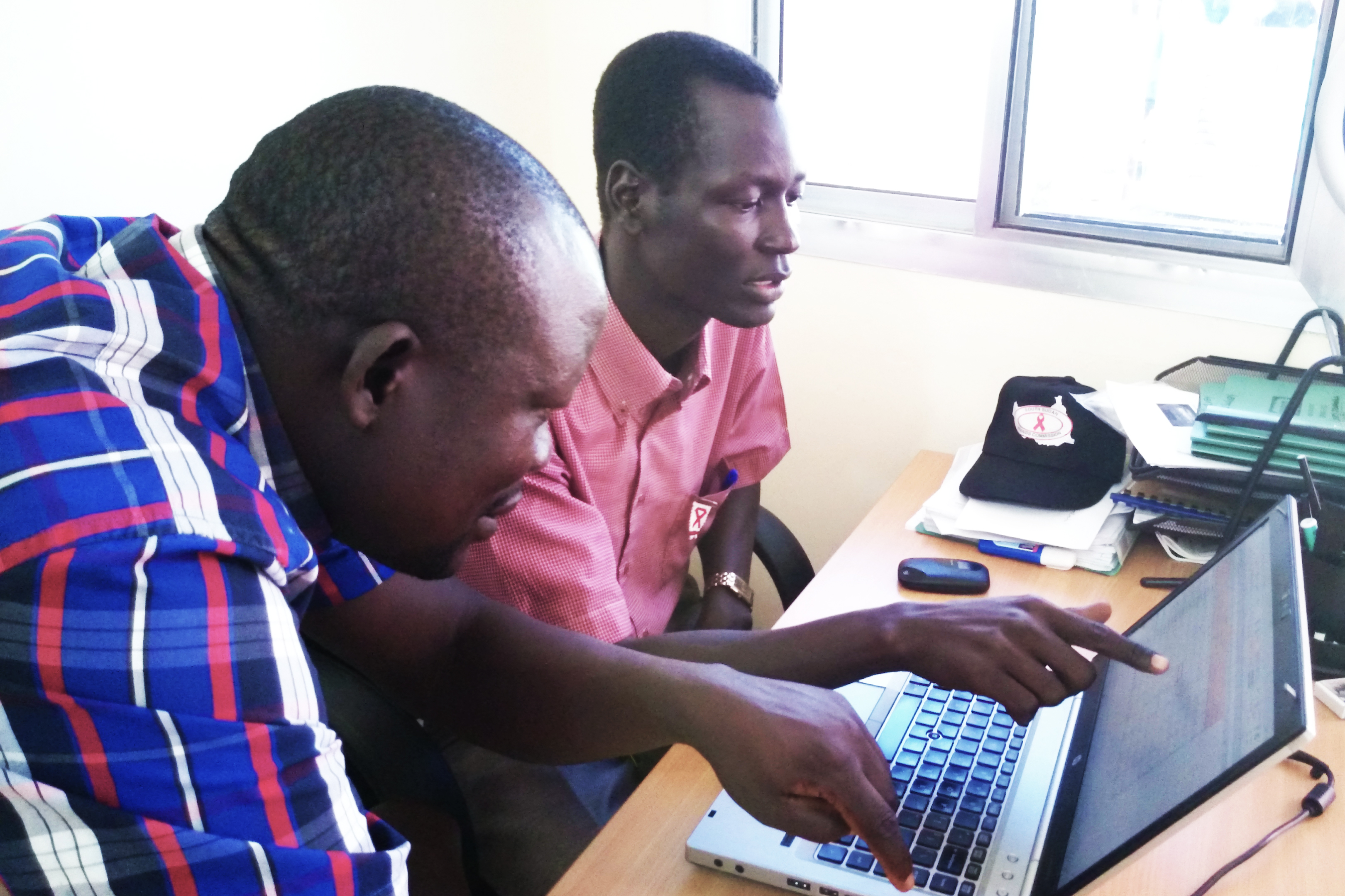 Acaga mentors and coaches Ajak and gives him hands-on training on the key aspects of data collection, analysis, dissemination, storage, and coordination among partners.